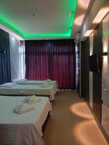 a room with three beds and a tv and green lights at Barış Otel in Didim