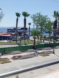 a park with palm trees and a building in the background at Barış Otel in Didim