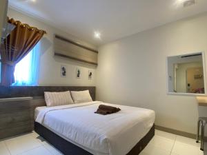 a bedroom with a large white bed with a mirror at Hotel Paris Santika in Rawara