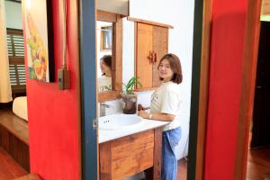 a woman standing in front of a bathroom sink at Khom Chiang Mai in Chiang Mai