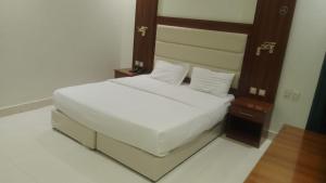 a bedroom with a white bed and a wooden headboard at فرس ابها - شقق مفروشه in Abha +23 photos