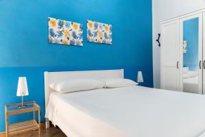 a bedroom with a white bed and blue walls at Appartamento Sunny by ThePuglia in Torre Lapillo
