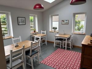 a dining room with two tables and chairs and windows at Ty Boia Bed & Breakfast in St. Davids