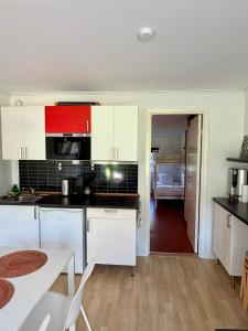 a kitchen with white cabinets and a table and a room at Hällestrand Semesterby R19 in Strömstad +11 photos