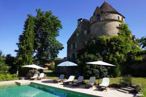 a pool with chairs and umbrellas in front of a castle at Mas De Garrigue - Chambres d'hôtes in Calvignac