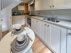 a kitchen with white cabinets and a table with wine glasses at Militia Cottage in Marlborough