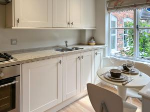 a kitchen with white cabinets and a table and a sink at Militia Cottage in Marlborough