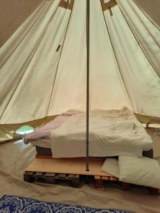 a bed in a canvas tent on a wooden platform at Glampingtält in Österbybruk