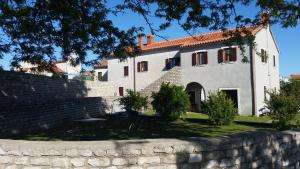 a white house with a brick wall and a table at Apartments Stella Apsyrtides in Osor