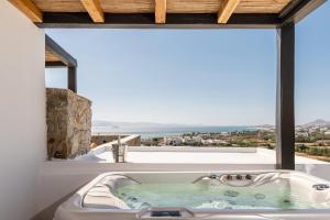 a bathroom with a bath tub with a large window at Lithia Exclusive Villas & Suites in Plaka