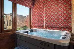 a bath tub in a room with a window at Jivaeri Luxury Suites in Rhodes Town