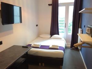 Habitación con 2 camas, escritorio y TV. en Hotel Bellington, en Ámsterdam