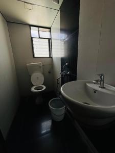 a bathroom with a sink and a toilet and a window at Sun N Shine in Pune
