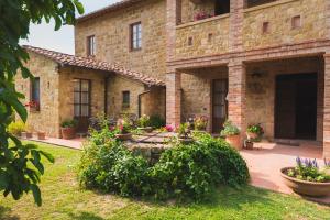 a stone house with flowers in a yard at Agriturismo Podere San Gregorio in Pienza