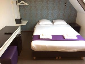 a bedroom with a bed with a purple and white mattress at Hotel Bellington in Amsterdam