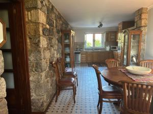 a kitchen with a table and chairs and a stone wall at Villa To Petrino in Vathís +44 photos