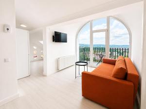 a living room with an orange couch and a large window at DD Apartments - Iuliu Moldovan in Cluj-Napoca