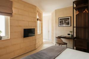 a bedroom with a stone wall with a tv and a desk at Casa Radiant in Rabat