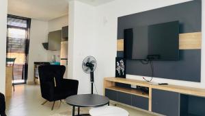 a living room with a desk and a tv on a wall at AGASARO LUXURY Apartment in Kigali