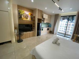 a room with a white bed and a kitchen at Vinhomes D'Capitale - Amee Apartment in Hanoi