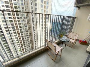 a balcony with two chairs and a table and large windows at Vinhomes D'Capitale - Amee Apartment in Hanoi