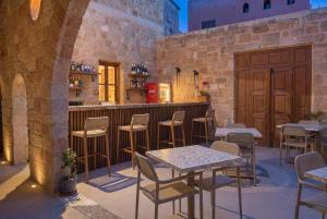 a patio with tables and chairs and a bar at Jivaeri Luxury Suites in Rhodes Town