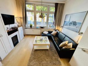 a living room with a black leather couch and a table at Ankerplatz in zentraler Lage in Warnemünde
