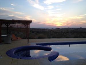 una piscina con puesta de sol en el fondo en Cortijo de los Castellanos en Las Ventanas