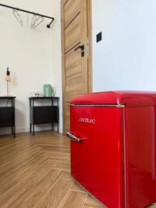 a red refrigerator in a room with a wooden floor at Szumi Las Bed & Breakfast in Józefów