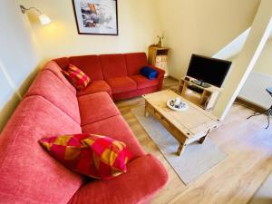 a living room with a red couch and a coffee table at Sonnendeck, direkt am Leuchtturm in Warnemünde