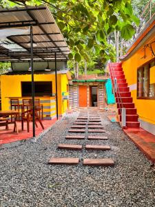 a walkway in front of a yellow building with stairs at Hope Hostels - Munnar in Munnar