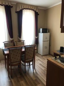 a dining room with a table and chairs and a refrigerator at Thermal Apartman 01 in Kiskőrös