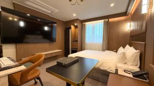 ein Hotelzimmer mit Bett, Schreibtisch und Fernseher in der Unterkunft Urban Brown Hotel in Gunsan