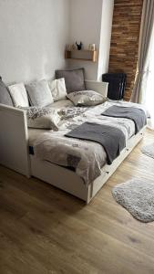 a white bed in a bedroom with a wooden floor at Charmant appartement avec balcon et parking privé in Lens