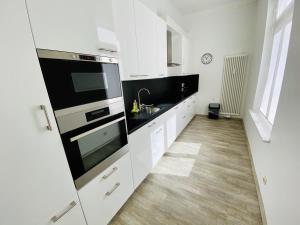 a kitchen with white cabinets and black appliances at Berringer, Knurrhahn, direkt an der Promenade in Warnemünde +7 photos