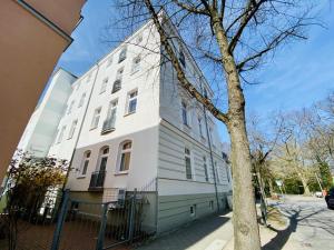 a white building with a tree in front of it at Traumstrand, am Kurpark in Warnemünde