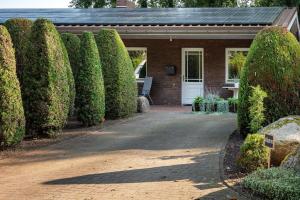 a house with a row of hedges in front of a driveway at Ferienwohnung Bahlmann in Garrel