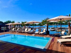 a swimming pool with chairs and umbrellas on a deck at Przystań Hotel&Restaurants in Olsztyn
