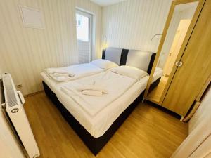 a bedroom with a large bed with white sheets at Haus Juliane, Lichtblick in Warnemünde