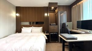 ein Hotelzimmer mit Bett und Schreibtisch mit Computer in der Unterkunft Urban Brown Hotel in Gunsan