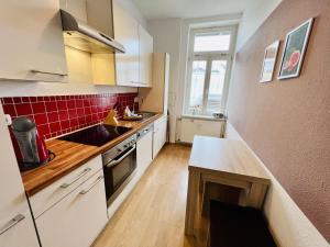 a kitchen with white cabinets and red tile on the wall at Haus Juliane, Neptun in Warnemünde