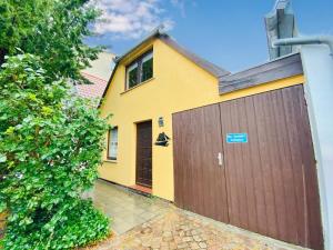 a yellow house with a brown garage at Ferienhaus Segelboot in Warnemünde