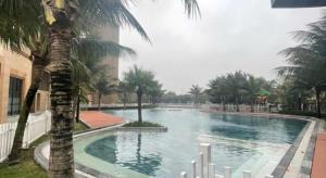a large swimming pool with a palm tree next to a building at Vinhomes D'Capitale - Amee Apartment in Hanoi