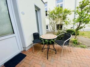 a patio with a table and three chairs on a patio at Haus Juliane, Seepferdchen in Warnemünde