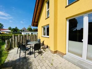 a patio with a table and chairs next to a yellow house at Ferienhaus Stoertebeker in Warnemünde