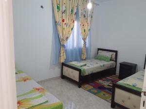 a bedroom with two beds and a window with curtains at Dar chat in Kelibia