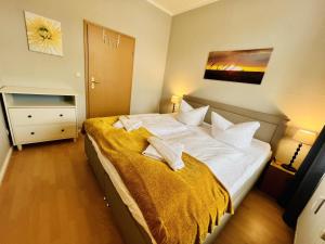 a bedroom with a large white bed with a yellow blanket at Haus Juliane, Strandliebe in Warnemünde