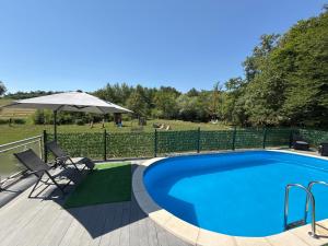 a swimming pool with an umbrella and two chairs and a table at 1001 Noc Cazin - Oaza prirode i odmora in Mutnik