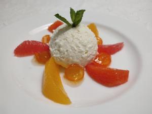a white plate with a scoop of ice cream and fruit at Hotel Landgut Burg in Weinstadt