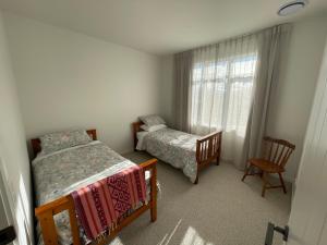 a small bedroom with two beds and a window at Modern home, old charm! in Lake Hāwea